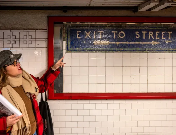 guide pointing at mosaic wall in subway station