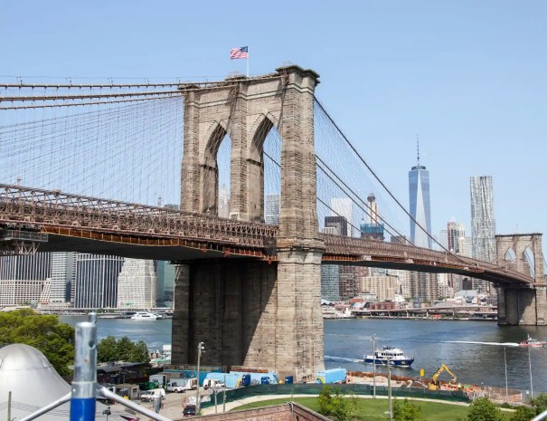 Panoramic view of the Brooklyn Bridge and skyline The Brooklyn Bridge spanning across the East River with the Manhattan skyline and One World Trade Center in the background, seen from the Brooklyn waterfront.