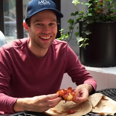 Man holding a slice of pizza on Taste of New York Tour with Untapped New York