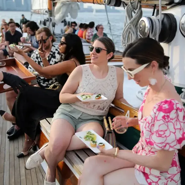 Two women sitting on a boat holding wine glasses at the Tides & Tapas tour