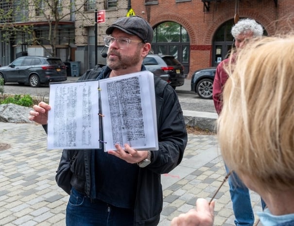 Untapped New York guide showing guests a reproduction of a handwritten historical document during the Spies of the American Revolution walking tour in lower Manhattan