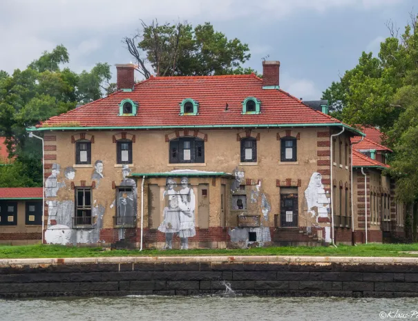 JR's Unframed photographs pasted on the walls of the abandoned Ellis Island hospital, seen from the water